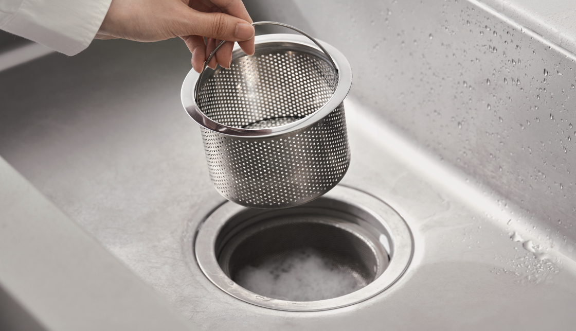 [라이프케어] 싱크대의 배수구 안에는 클리너 거품이 있고 손으로 배수구망을 들고 있습니다.