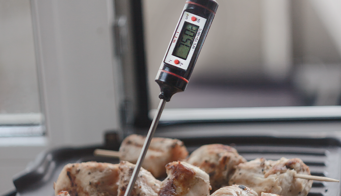 [라이프케어] 꼬치에 끼운 고기가 불판 위에 있고 불판 온도를 재고 있는 온도계에는 75도가 표시되어 있습니다.