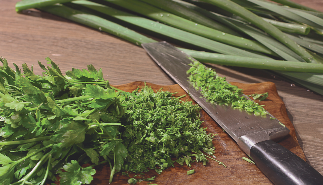 [라이프케어] 도마위에 잘게 잘린 파슬리가 있고 옆에 놓인 칼에는 파슬리 잔여물이 남아있습니다. 