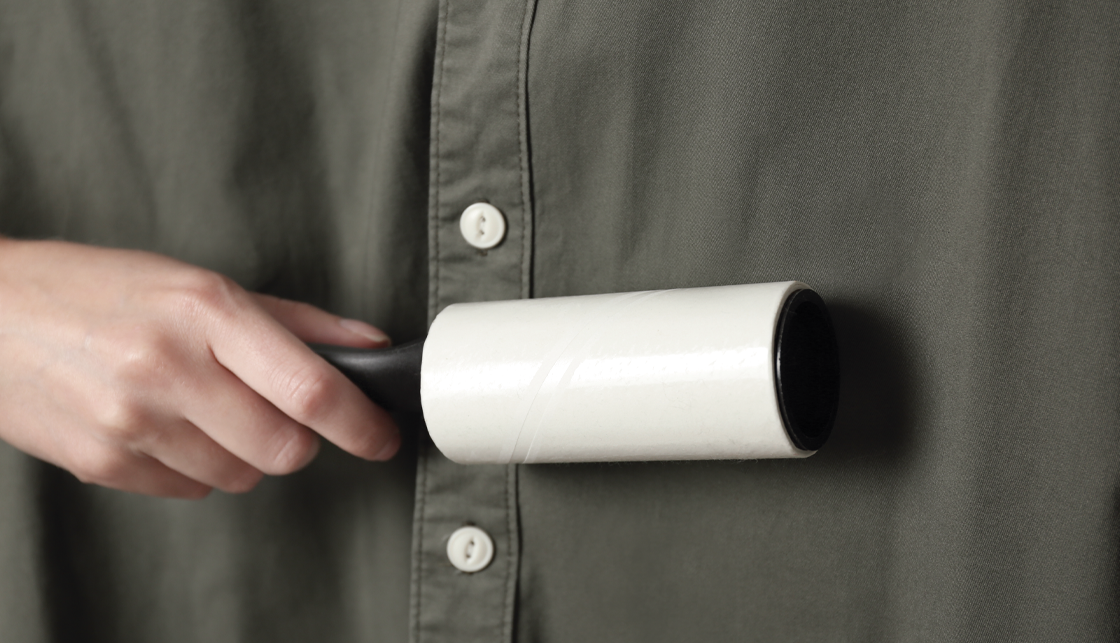 [라이프케어] 어두운 컬러의 셔츠를 테이프 클리너로 정리하고 있는 모습입니다.